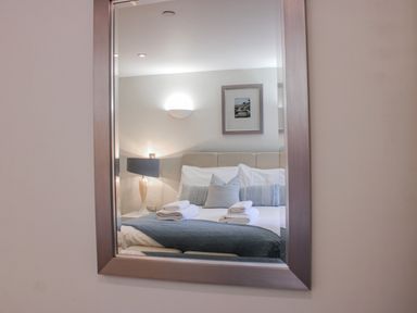 A reflection of a bedroom with a bed and lamp at Estuary View in Kingsbridge