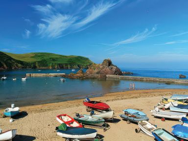 A beach with boats on the sand and people walking at Estuary View in Kingsbridge