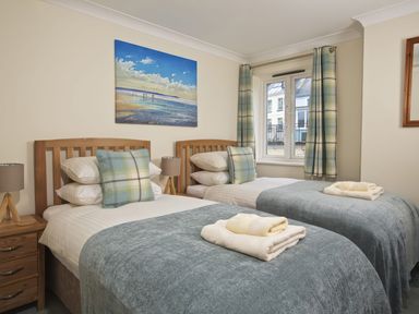 A bedroom with two single beds pillows lamps and a window at Bakers Dozen 13 Dartmouth House Dartmouth