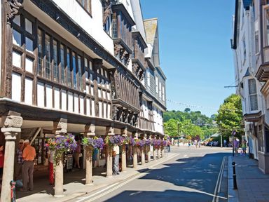 A street with timber-framed buildings and flower baskets on columns at Bakers Dozen 13 Dartmouth House Dartmouth
