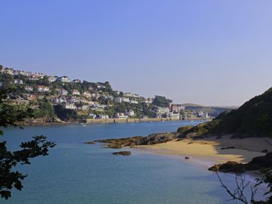 A coastal view with houses on a hill and a sandy beach at 14a Courtenay Street in Salcombe