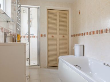 A bathroom with a bathtub a toilet a shower enclosure and a sink with cabinets at 14a Courtenay Street in Salcombe