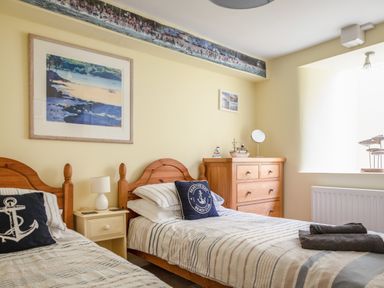 A bedroom with two single beds a wooden chest of drawers and seaside-themed decorations at 14a Courtenay Street Salcombe