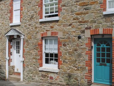 Stone wall with two doors and two windows on a street at 14a Courtenay Street in Salcombe