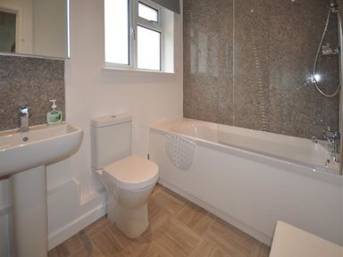 A bathroom with a sink toilet bathtub shower and window at Pebbles in Burton Bradstock
