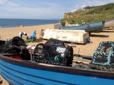 A beach with fishing boats and fishing equipment on the sand at Pebbles in Burton Bradstock