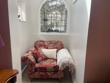 An armchair with a cushion and blanket at Pedaller's Cottage in Weymouth