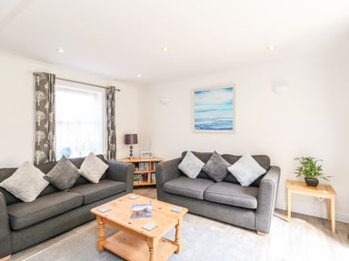 A living room with two grey sofas and a wooden coffee table with books at The Pines in Weymouth