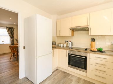 A kitchen with white cabinets a refrigerator an oven and countertop items at The Pines in Weymouth
