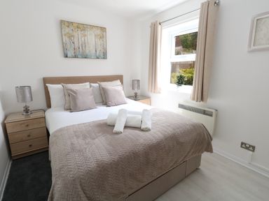 A bedroom with a double bed bedside tables lamps and a window at The Pines in Weymouth