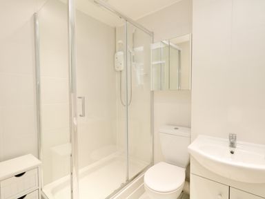 A bathroom with a glass shower enclosure a toilet and a sink at The Pines in Weymouth
