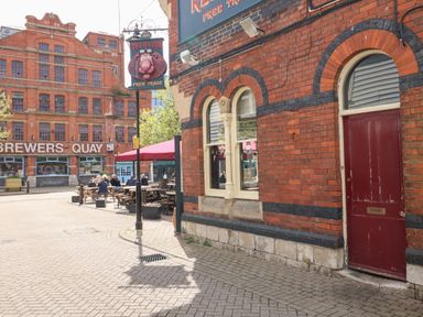 A pub with outdoor seating and a red door near a building with Brewers Quay sign at Brewers Quay Harbour