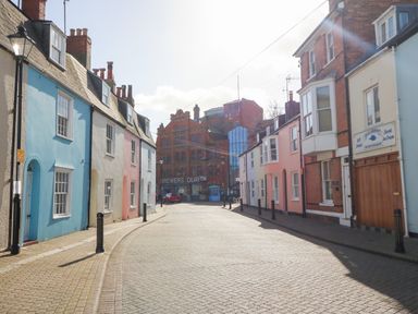 A street with pastel colored houses and a large brick building with Brewers Quay sign at Brewers Quay Harbour
