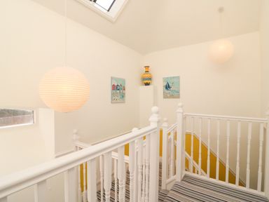 A stairwell with white railings two hanging lights striped carpet and wall art at Poppies in Brewers Quay Harbour