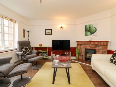 A living room with two gray recliner chairs a white sofa a TV on a stand and a fireplace at Poppies Brewers Quay Harbour