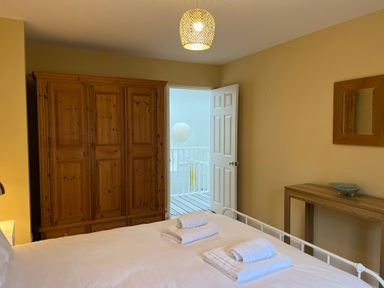 A bedroom with a wooden wardrobe a bed with white linens folded towels a wooden table and a wall mirror at Poppies Brewers Quay Harbour
