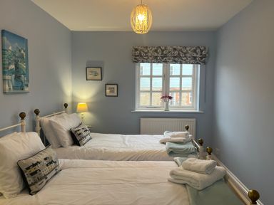 A bedroom with two single beds a window and a lamp at Poppies in Brewers Quay Harbour