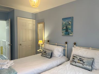 A bedroom with two single beds a lamp and a painting on the wall at Poppies Brewers Quay Harbour
