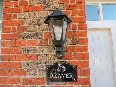 A black outdoor wall lantern above a black nameplate reading Reaver on a red and gray brick wall at Brewers Quay harbour