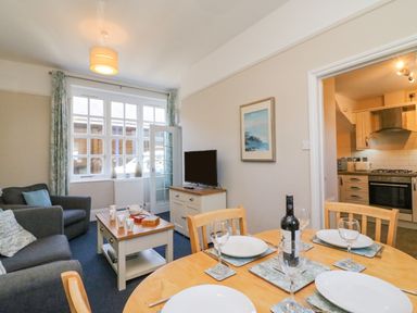 A dining table set with plates and wine bottle next to a living area with sofas and a TV at Reaver Brewers Quay harbour