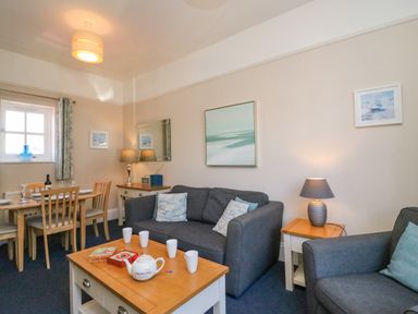 A living room with gray sofas a wooden coffee table and a dining table with chairs at Reaver Brewers Quay harbour