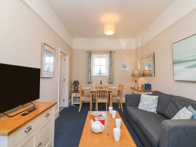A living room with a gray sofa coffee table and dining table with chairs at Reaver in Brewers Quay harbour