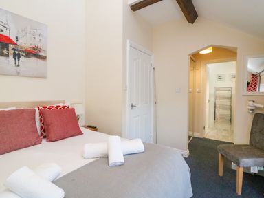 A bedroom with a bed pillows towels chair and door leading to a bathroom at Reaver Brewers Quay harbour