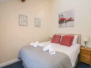 A bedroom with a double bed red and white pillows bedside tables with lamps and paintings on walls at Reaver Brewers Quay harbour