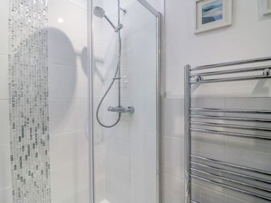 A shower enclosure with a chrome showerhead and tiled walls next to a chrome heated towel rail in a bathroom at Reaver Brewers Quay harbour