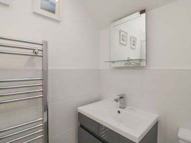 A bathroom with a sink and faucet a towel rack and a mirror with framed pictures reflected at Reaver in Brewers Quay harbour