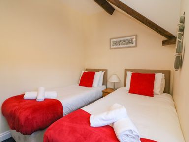 A bedroom with two single beds with red throws and pillows and white towels on the beds at Reaver Brewers Quay harbour