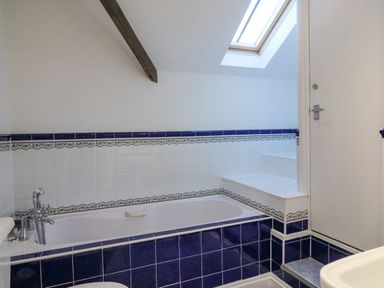 A bathroom with a bathtub tiled in blue and white and a skylight at Reaver Brewers Quay harbour