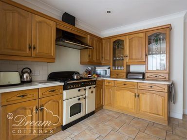 A kitchen with wooden cabinets a stove a microwave a toaster and a kettle at Redcliff View Lodge in Weymouth