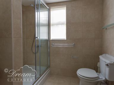 A bathroom with a shower enclosure, a toilet, and two towel bars at Redcliff View Lodge in Weymouth