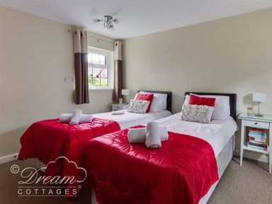 A bedroom with two single beds with red bedding and white bedside tables at Redcliff View Lodge in Weymouth