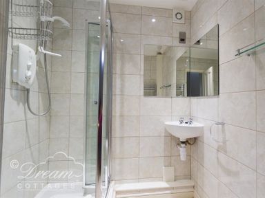 A bathroom with a shower enclosure a wall-mounted sink and a mirror at Redcliff View Lodge in Weymouth