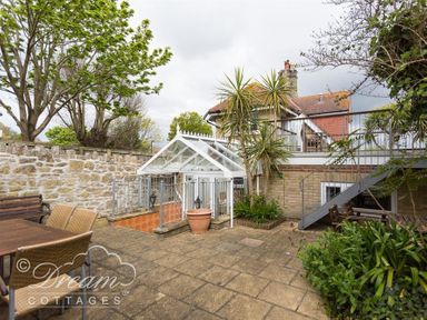 An outdoor patio area with a dining table and chairs stone wall stairs and plants at Redcliff View Lodge in Weymouth