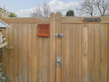 A wooden gate with a latch and two signs one saying River Cottage and the other Please Shut The Gate at River Cottage Burton Bradstock