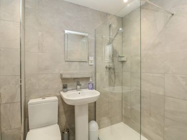 A bathroom with a toilet sink mirror and a walk in shower at Rockpools in Weymouth