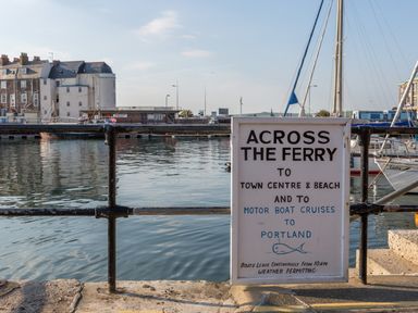 A waterfront area with a sign about ferry and motor boat cruises near boats and buildings at Rockpools in Weymouth