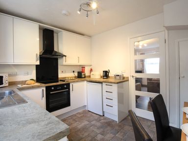 A kitchen with white cabinets electric oven toaster and microwave at Rockpools in Weymouth