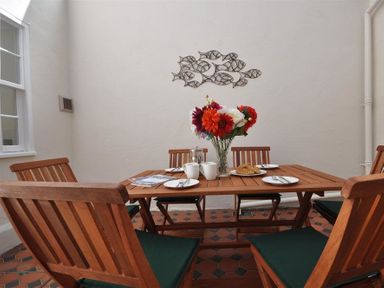 A dining area with wooden table and chairs set with plates cups flowers and pastries at Safe Harbour Brewers Quay harbour