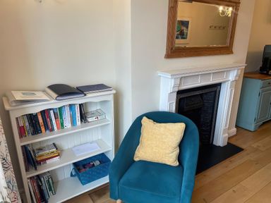 A living room with a bookshelf and blue chair at Safe Harbour in Brewers Quay harbour