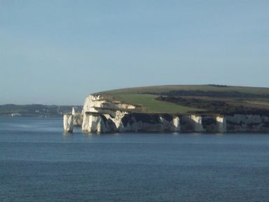 A coastal cliff with white chalk formations and green grass above at Sanjernin in Swanage