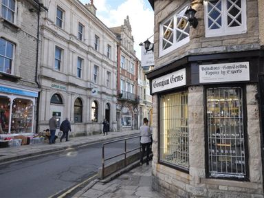 A street view with pedestrians walking past shops including Georgian Gems and Lloyds Bank at Sanjernin in Swanage