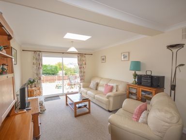 A living room with leather sofas a wooden coffee table and a sliding glass door leading outside at Sanjernin Swanage