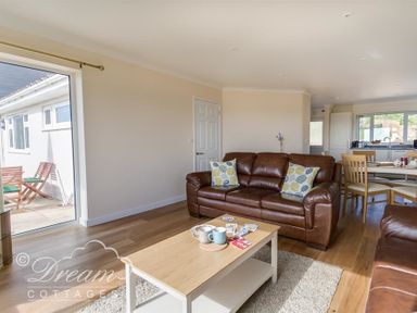 A living room with brown leather sofas a wooden coffee table and dining table with chairs at Seacliff in West Bay