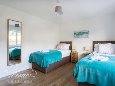 A bedroom with two single beds with turquoise blankets and wooden nightstands between at Seacliff in West Bay