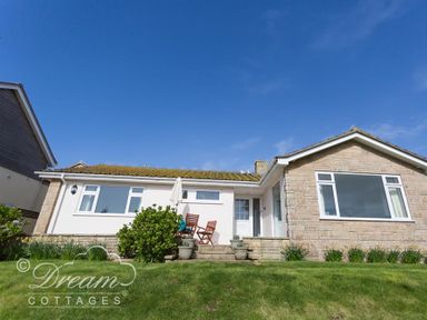 A single story house with a lawn and outdoor chairs at Seacliff in West Bay