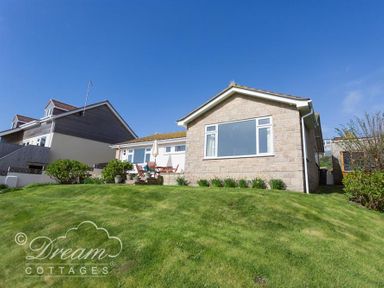 A house with a grass lawn and outdoor table and chairs under a clear blue sky at Seacliff in West Bay